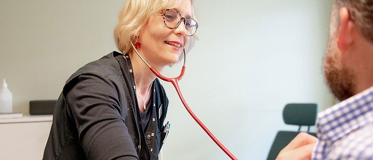 En kvinna med stetoskop undersöker en person